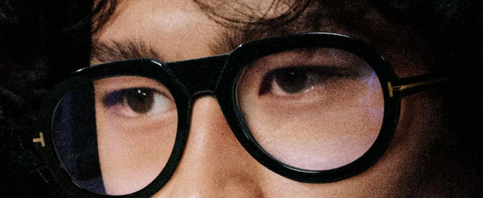 A close-up of a model wearing round Tom Ford glasses
