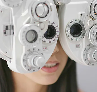 A child looking through a phoropter during an eye examination