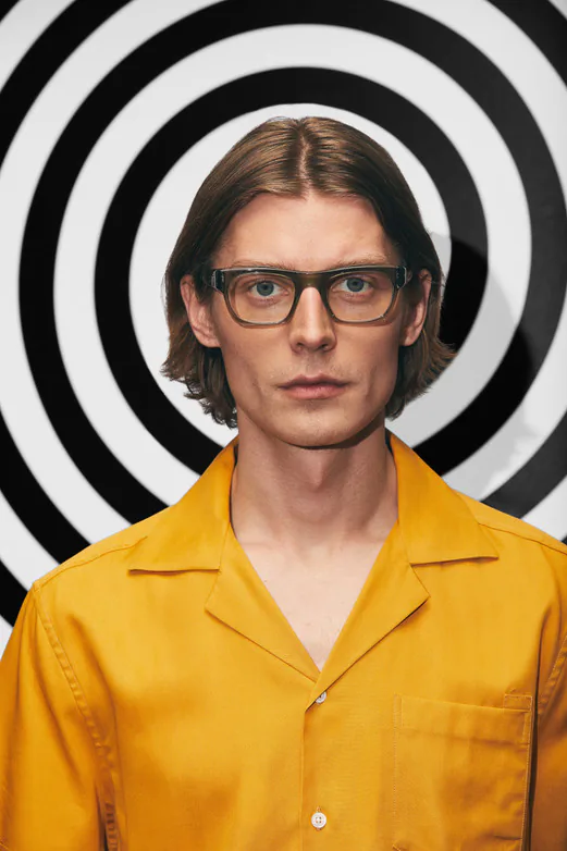 A model wearing glasses against a spiral backdrop
