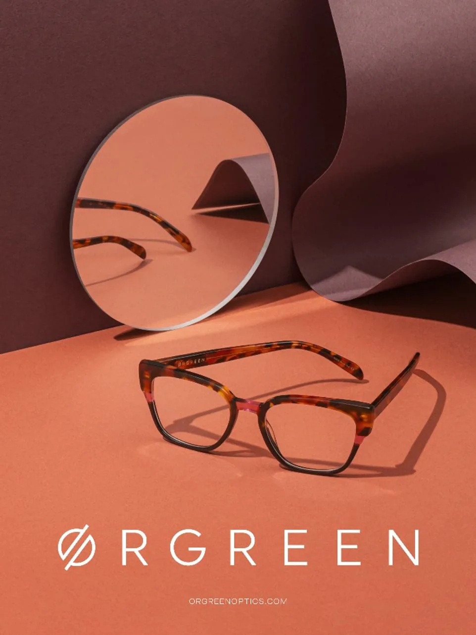 Two pairs of Orgreen glasses beside a circular mirror