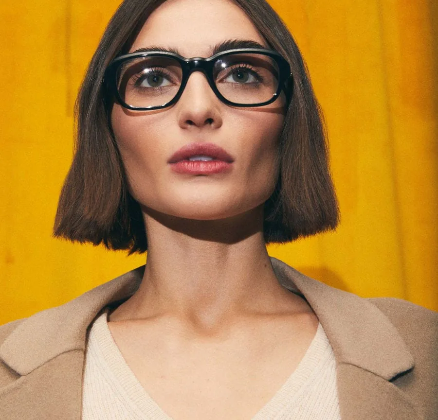 A model wearing glasses against a yellow background